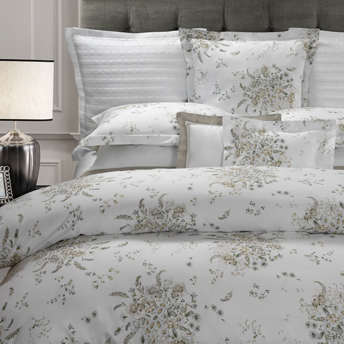 Alena pillowcase sham and duvet cover on a bed with a lamp and headboard in the background.