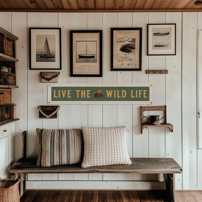 Forager Provisions LTD Benoit Design Co felt banner with Live The Wild Life text and bear graphic on a white wall.