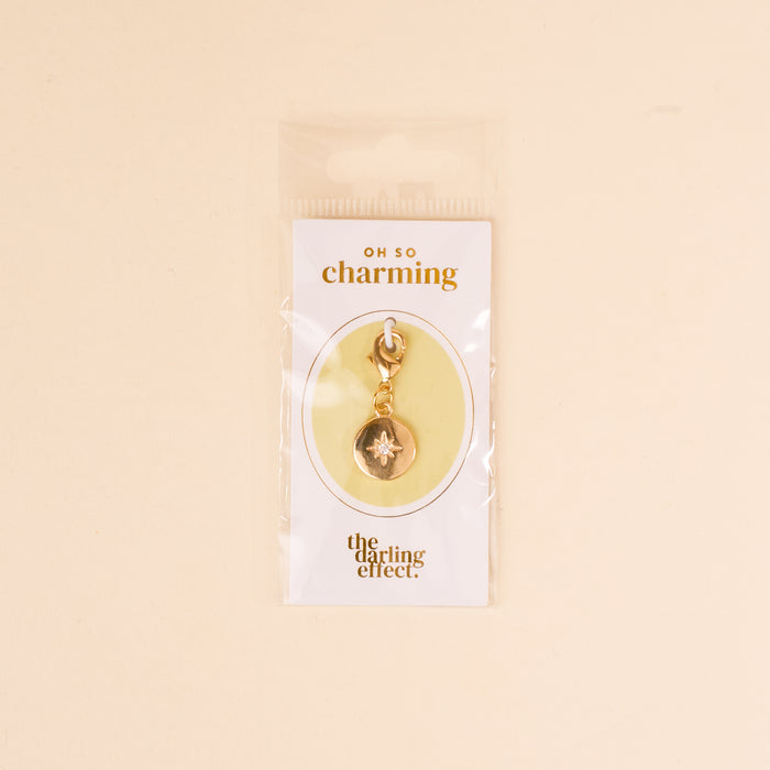 The Compass Jewelry Charm Gold by the-darling-effect comes on a white card labeled 'OH SO charming' and is packaged in a clear bagโan ideal addition to your charm bar collection.
