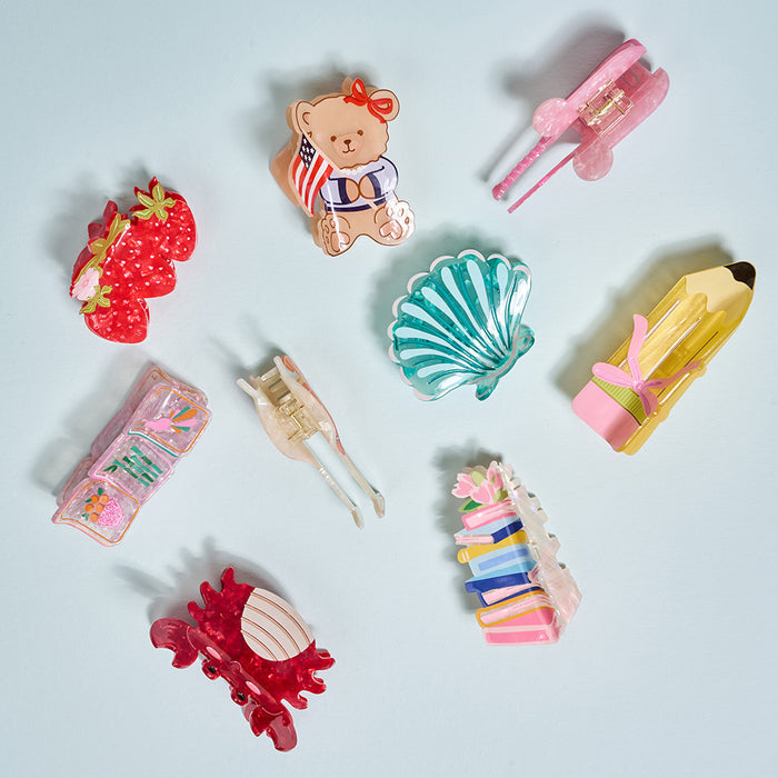 A flat lay of The Darling Effectโs Cowgirl Boot Shape Up Claw Clipโa cute, colorful hair accessoryโon a light blue background.
