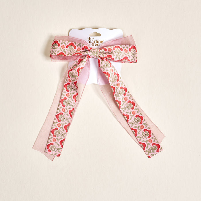 The Everbloom Dusty Rose Lovely Layered Hair Bow by The Darling Effect is a charming pink floral hair accessory with red and gold accents, tied in a bow and displayed on a white card against a light background.