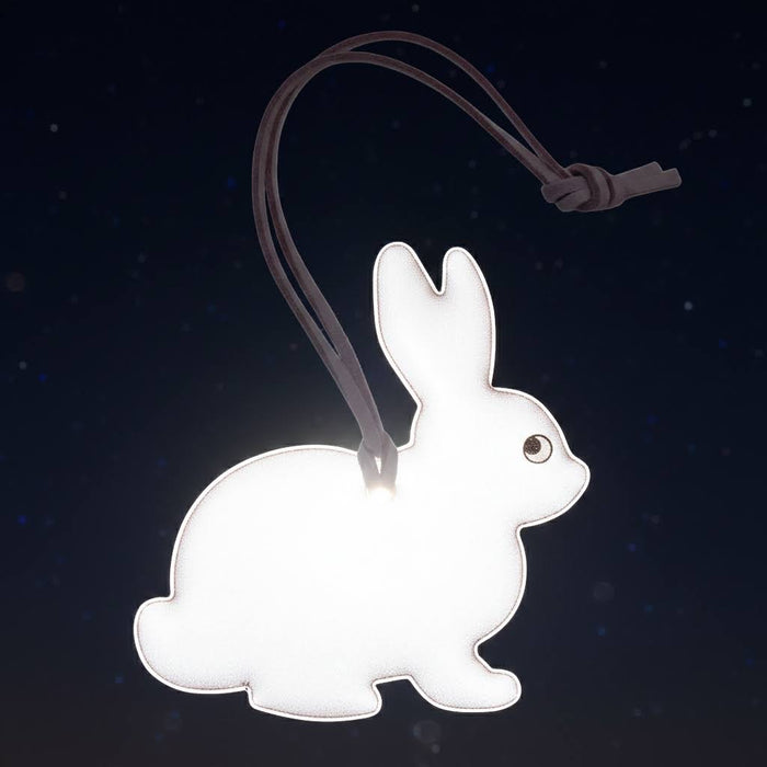 Forager Provisions LTD Firefly Sweden pink bunny reflective bag charm glowing against a dark night sky background