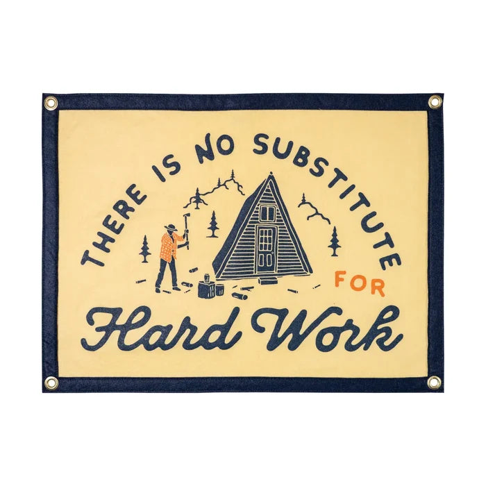 Oxford Pennant flag with โThere Is No Substitute For Hard Workโ as person chops wood at mountain cabin. Motivation outdoors.