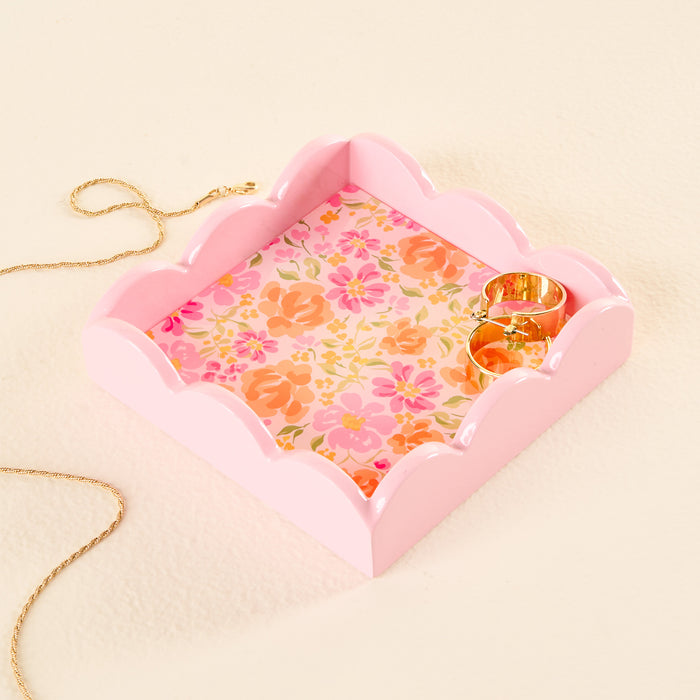 The Secret Garden Pink Scallop Trinket Tray by the-darling-effect, featuring a delicate floral pattern, elegantly displays a gold chain necklace and two gold rings, functioning beautifully as both an accessory tray and a practical jewelry organizer on a light-colored surface.