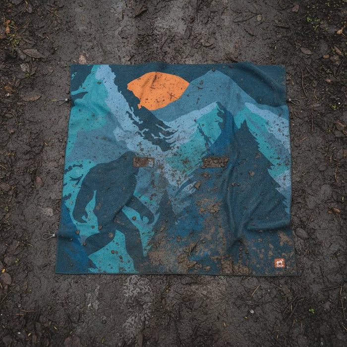 Forager Provisions LTD Sprints Big Foot party size towel and car seat cover with a moonlit forest print on mud ground.