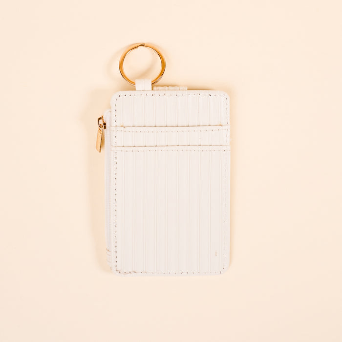 The Darling Effectโs White Ripple Ridge Keychain Wallet features vertical stitching, a zippered coin pocket, two card slots, and a gold key ring, shown on a light beige background.