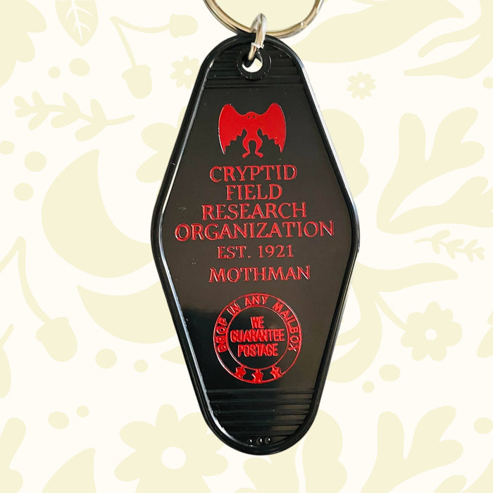 Forager Provisions LTD vintage style black plastic motel key fob with red Mothman and Cryptid Research Org graphics.