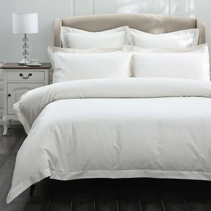 500TC Egyptian Cotton Ivory Duvet Cover Set on a bed with a nightstand and lamp in the background.