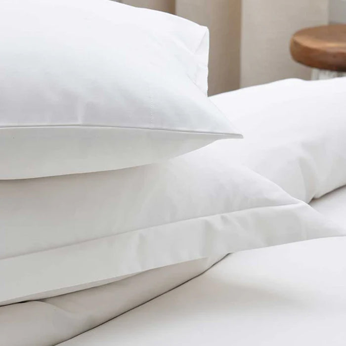 500TC Egyptian Ivory Cotton Flat Sheet on a bed with a wooden stool in the background.