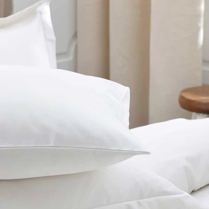 500TC Egyptian Cotton White Pillowcase on a bed with a neutral-colored curtain in the background.