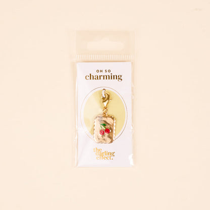 Add a playful touch to your jewelry with The Darling Effect's "A Cherry Moment Jewelry Charm Gold," featuring two red cherries on a stem and lobster clasp. Arrives on a white card with OH SO charming and The Darling Effect branding.