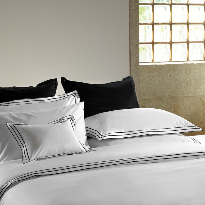 alba_white_black_sham pillowcase and duvet cover on a bed in a room with a window.
