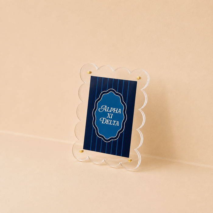 The Darling Effect Alpha Xi Delta Mini Acrylic Picture Frame Magnet features a clear, scalloped-edge design with gold screws and a blue Alpha Xi Delta card—ideal for adding sorority style to your mini fridge or displaying polaroids.