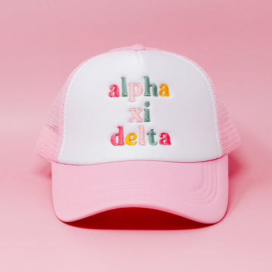 The Darling Effect’s Alpha Xi Delta Pink Trucker Hat features colorful embroidered letters on the front and is shown against a pink background.