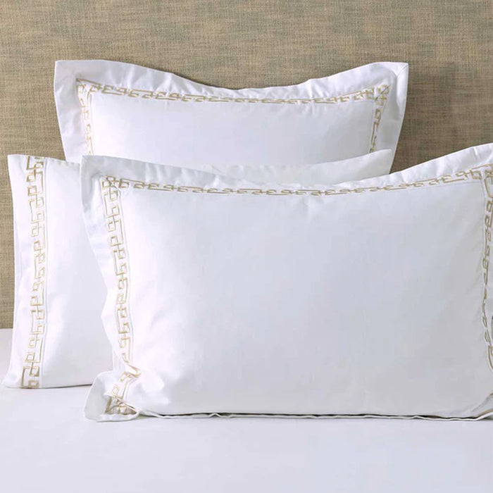 Ares Champagne Pillowcases and Cushions on a bed against a beige wall.