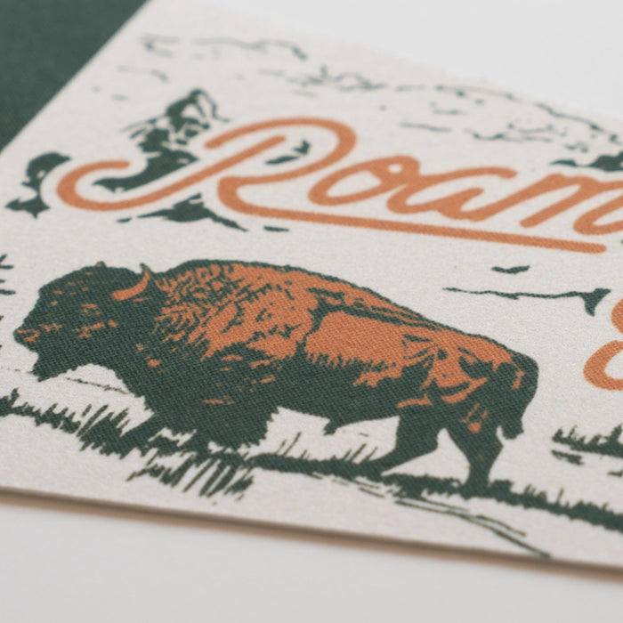 Close-up of "Roam Wild & Free" 8x28.5” felt pennant with bison, orange cursive letters, ideal wall decor gift for home or office.