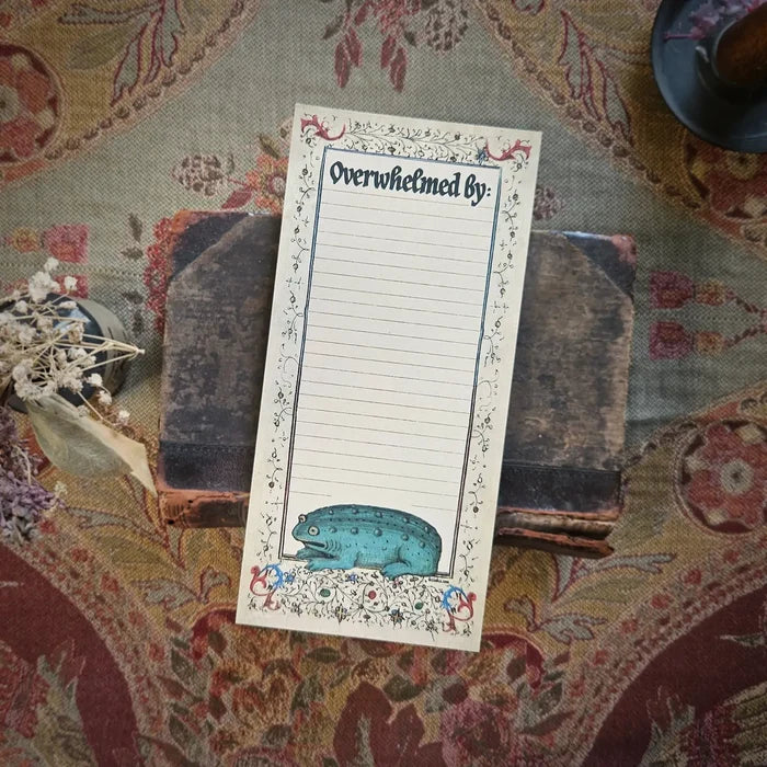 Betiobca “Overwhelmed By” Notepad features a blue medieval frog resting on an old book with ornate patterned background.