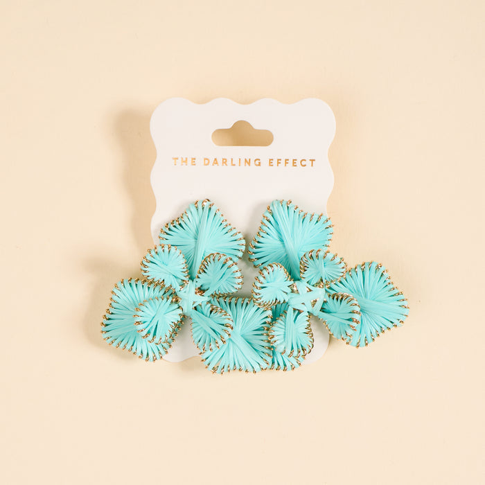 A pair of light blue fan-shaped "Blue Main Character Earrings" by The Darling Effect, with gold edges, perfect for everyday wear, displayed on a white card labeled THE DARLING EFFECT in gold text and set against a beige background.