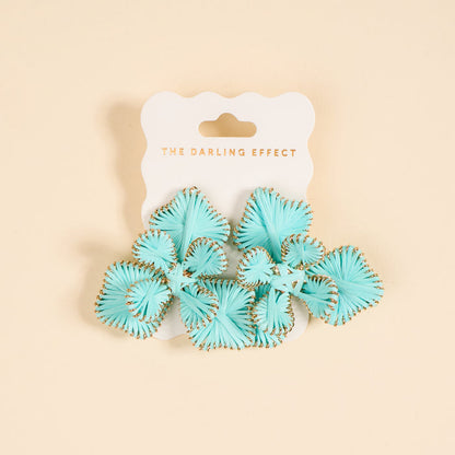 A pair of light blue fan-shaped "Blue Main Character Earrings" by The Darling Effect, with gold edges, perfect for everyday wear, displayed on a white card labeled THE DARLING EFFECT in gold text and set against a beige background.