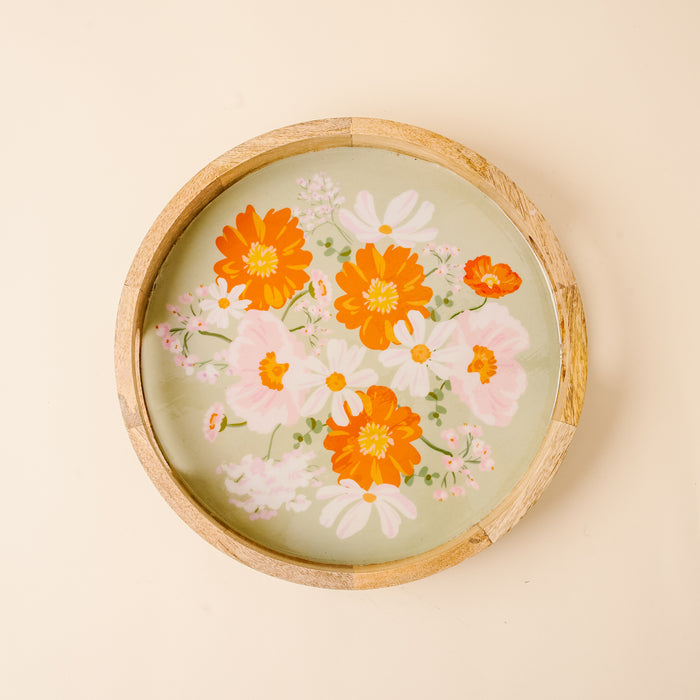 The-darling-effect’s Bouquet Beauty Sage Large Round Wood Enamel Tray features a light green base and painted orange, white, and pink flowers with green leaves on a beige background.