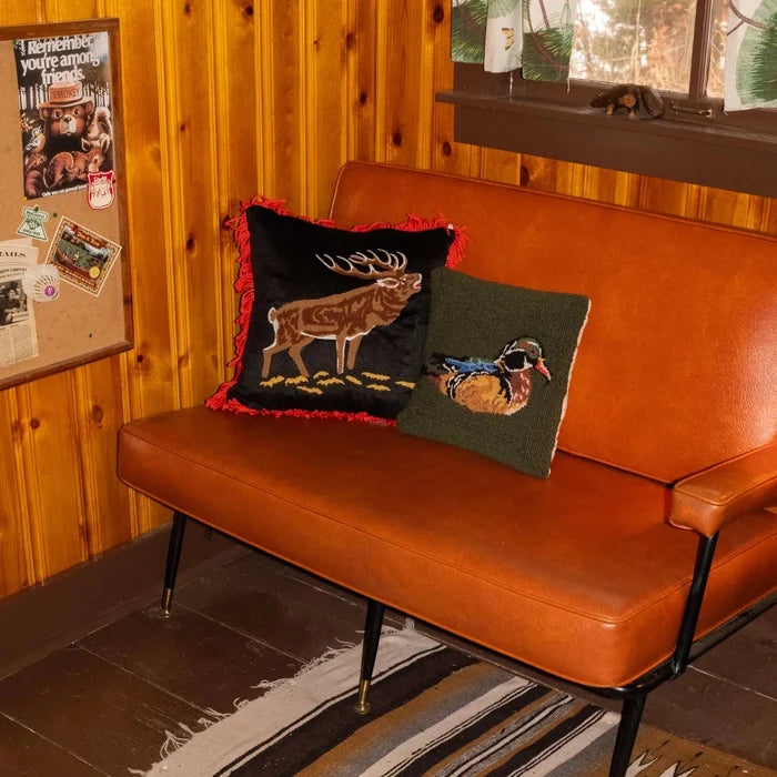 Brown loveseat with 18x18 Peking Camp Wandawega Elk Pillow; perfect rustic lodge accent for wood-paneled room decor.