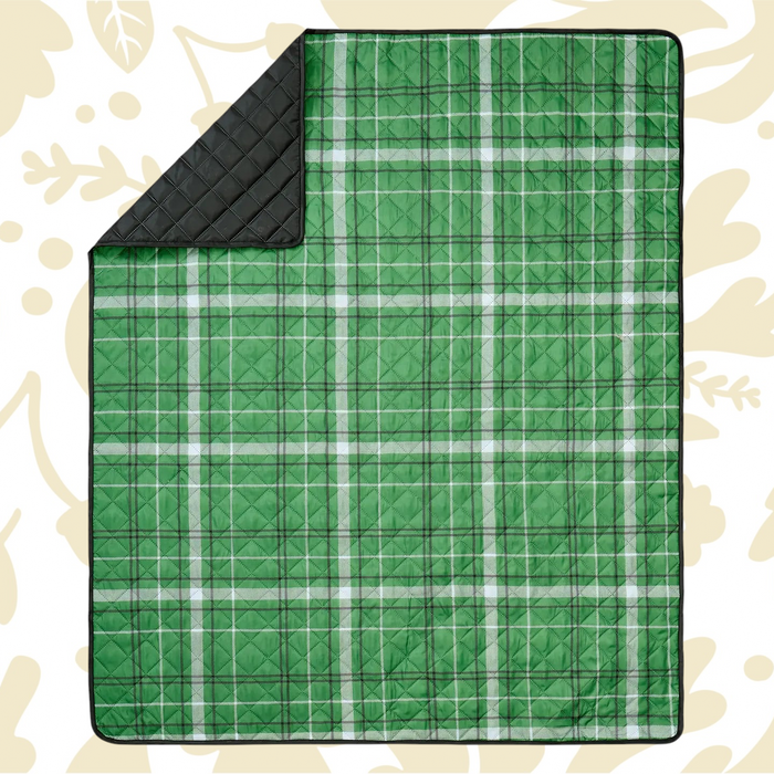 Shop the Peking Camp Wandawega picnic blanket with black lining, displayed on a beige leaf-patterned surface for outdoor use.
