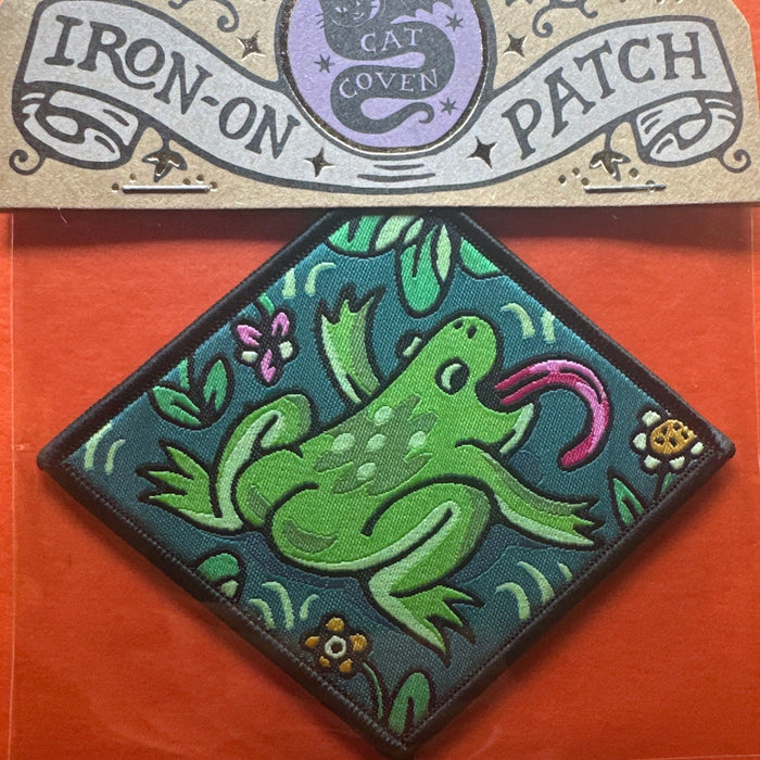 Forager Provisions LTD Cat Coven woven patch featuring a green frog with a pink tongue on a teal diamond background.