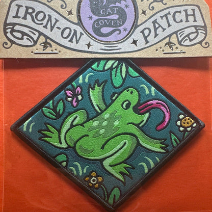 Forager Provisions LTD Cat Coven woven patch featuring a green frog with a pink tongue on a teal diamond background.