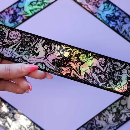 Hand holding Cat Coven holographic sticker featuring fantasy rabbits and skeletons—unique animal art collectible for sticker fans.