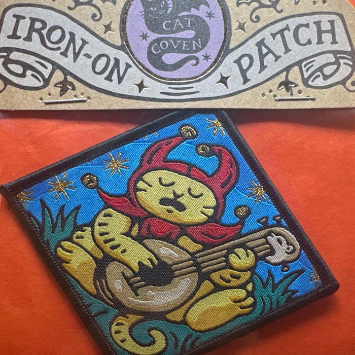 Cat Coven Sad Jester Cat woven patch: gothic jester cat, guitar, stars; blue on orange. Unique emo cat gift by Cat Coven.