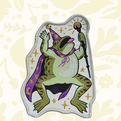 Forager Provisions LTD Cat Coven woven patch featuring a green toad wizard in a purple cape with gold star details.