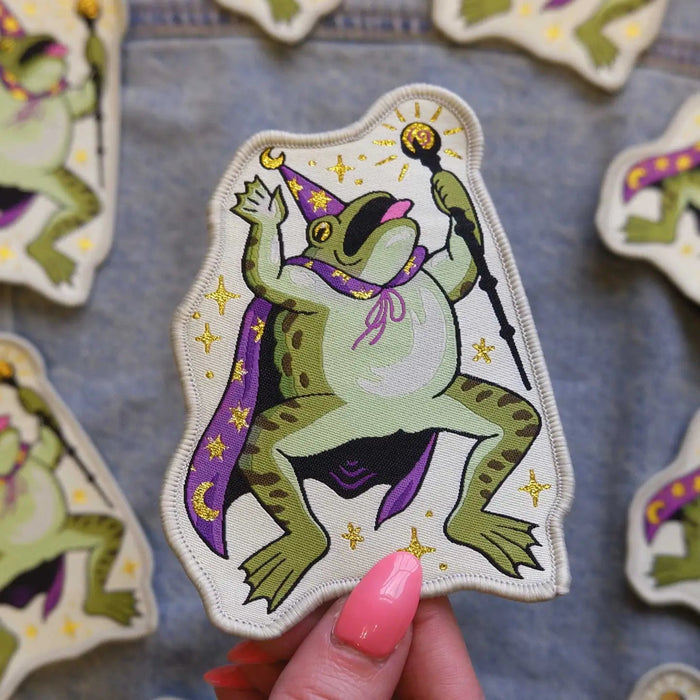 Forager Provisions LTD Cat Coven woven patch featuring a green toad wizard in a purple cape holding a staff.