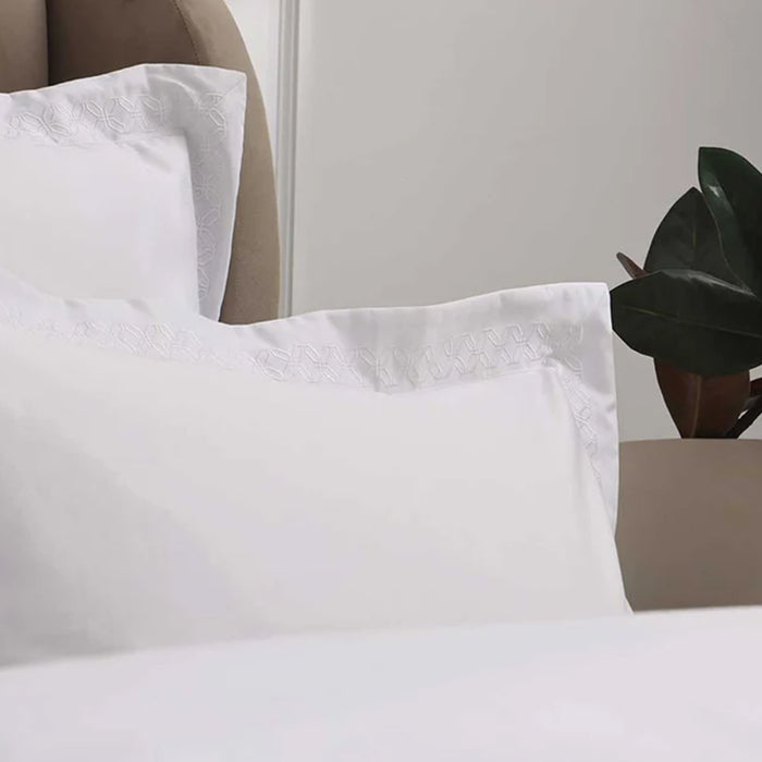 Cavendish White Pillowcase on a bed with a neutral headboard and plant in the background