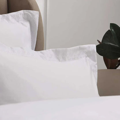 Cavendish White Pillowcase on a bed with a neutral headboard and plant in the background