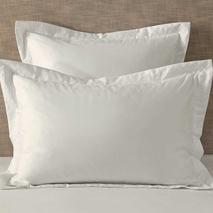 Cavendish Latte Pillowcase on a bed with a beige headboard.