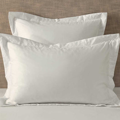 Cavendish Latte Pillowcase on a bed with a beige headboard.