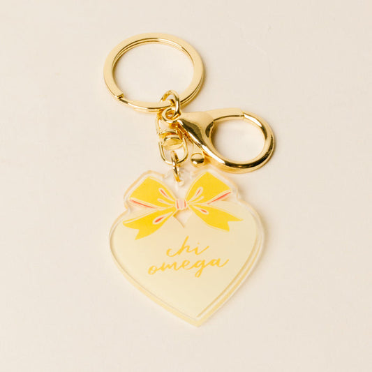 The Darling Effect’s Chi Omega Sweetheart Bow Acrylic Keychain features a gold lobster clasp, pastel bow, and “chi omega” in the center—perfect as a charming sisterhood gift.