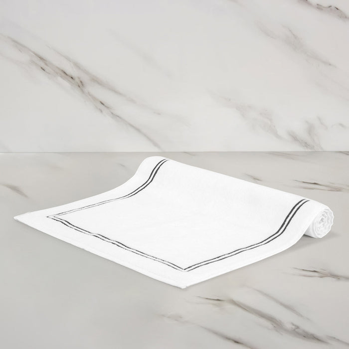 folded side of of a white grey classic bath mat on a marbeled surface and background