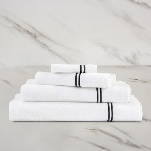 folded white grey classic guest towel stacked on other classic towels on a marbeled surface and background