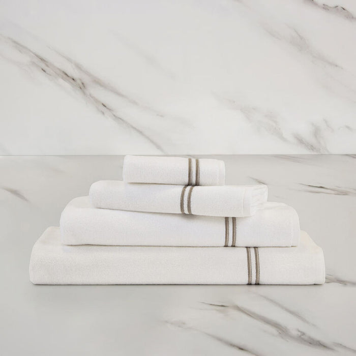 folded white khaki classic guest towel stacked on other classic towels on a marbeled surface and background