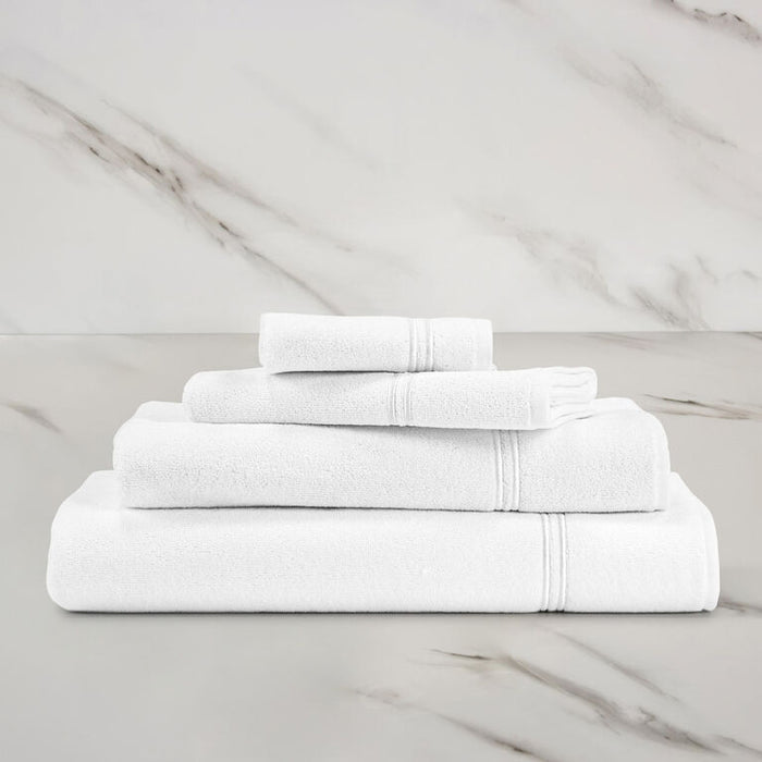 folded white white classic guest towel stacked on other classic towels on a marbeled surface and background
