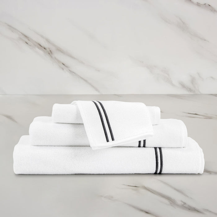 unfolded white grey classic wash cloth stacked on other classic towels on a marbeled surface and background