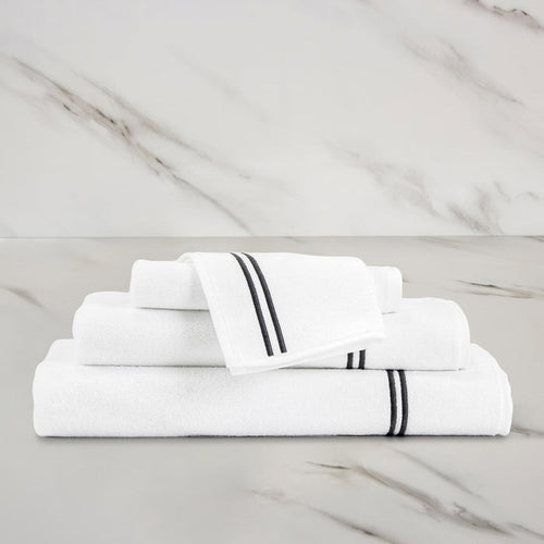 unfolded white grey classic wash cloth stacked on other classic towels on a marbeled surface and background
