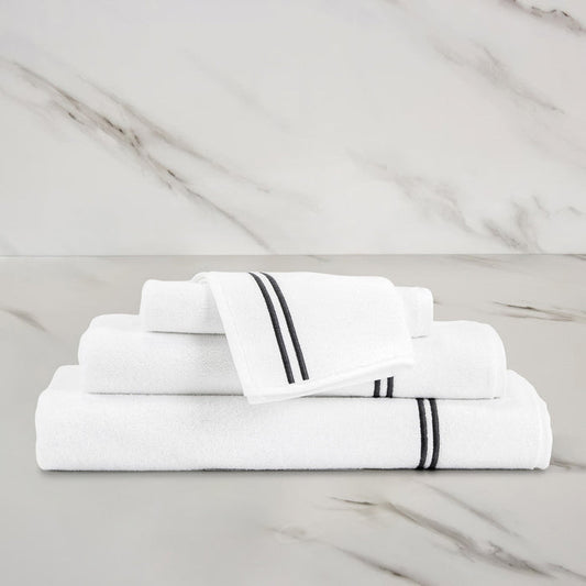 unfolded white grey classic wash cloth stacked on other classic towels on a marbeled surface and background