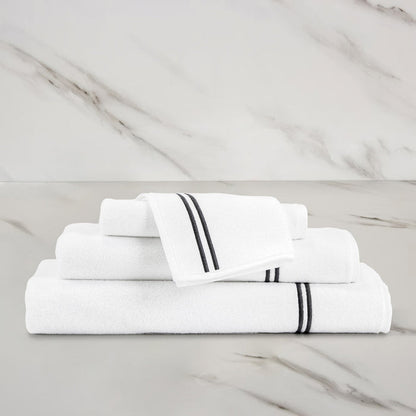 unfolded white grey classic wash cloth stacked on other classic towels on a marbeled surface and background