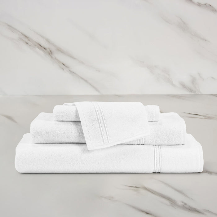 unfolded white white classic wash cloth stacked on other classic towels on a marbeled surface and background