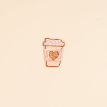 The Darling Effect's Coffee Cup Mix & Match Iron-On Patch features a light pink embroidered cup with a golden heart on a light yellow background—perfect for adding colorful flair to your collection.