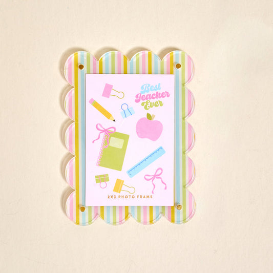 The Darling Effect's Color Me Happy Mini Acrylic Picture Frame Magnet features pastel scalloped stripes, a card with school supplies and “Best Teacher Ever” in pink and blue, plus “2x3 Photo Frame.” Perfect for displaying polaroids on your fridge.