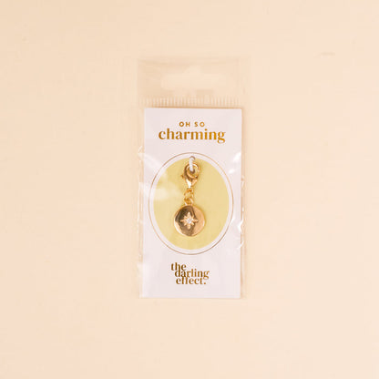 The Compass Jewelry Charm Gold by the-darling-effect comes on a white card labeled 'OH SO charming' and is packaged in a clear bag—an ideal addition to your charm bar collection.