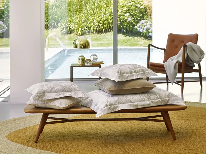 Wooden bench with Copacabana pillowcase sham in a modern room with a view of greenery